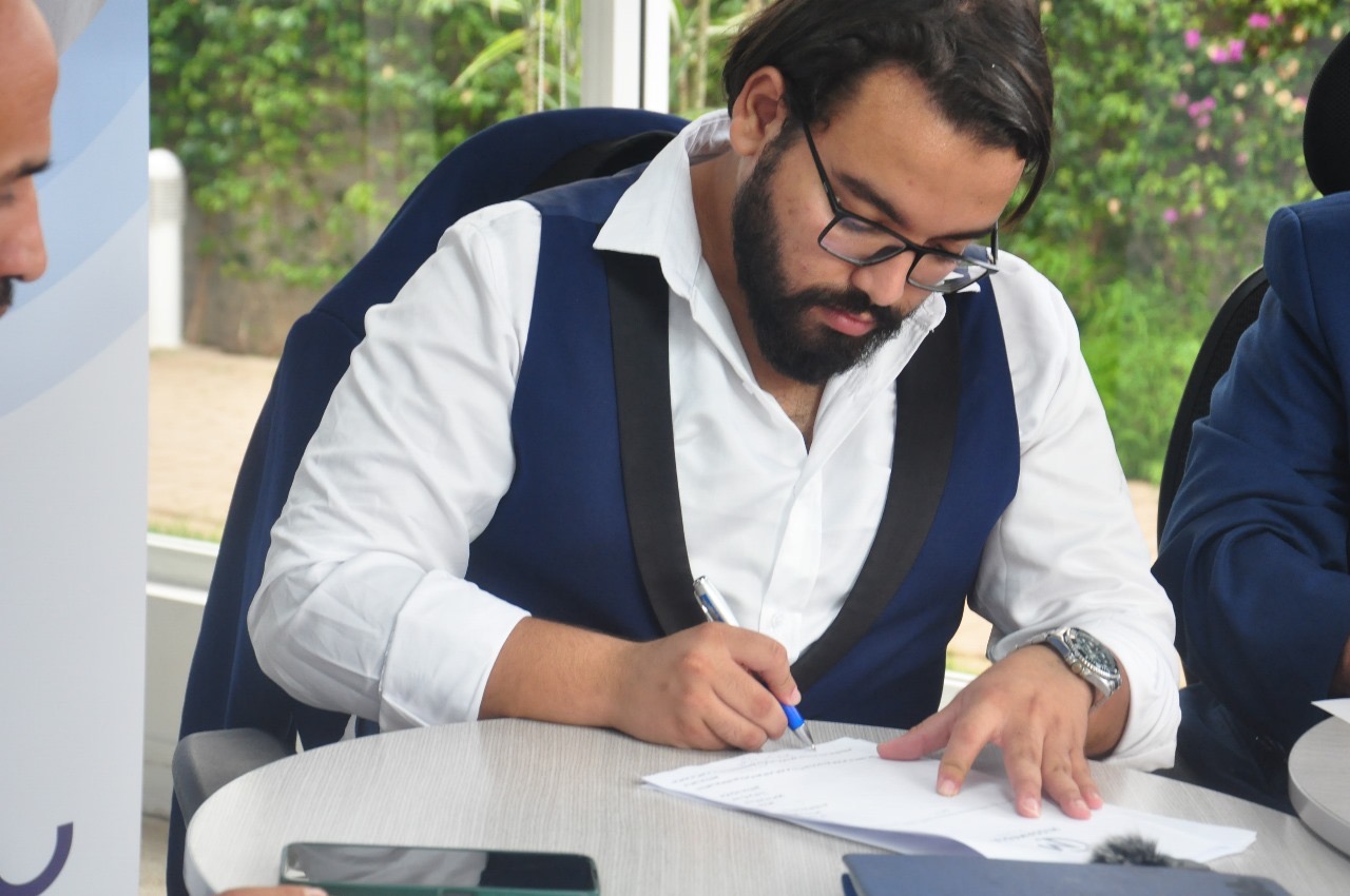 Mohamed Amine Missaoui signing a professional contract or partnership document at a formal business meeting, executive setting